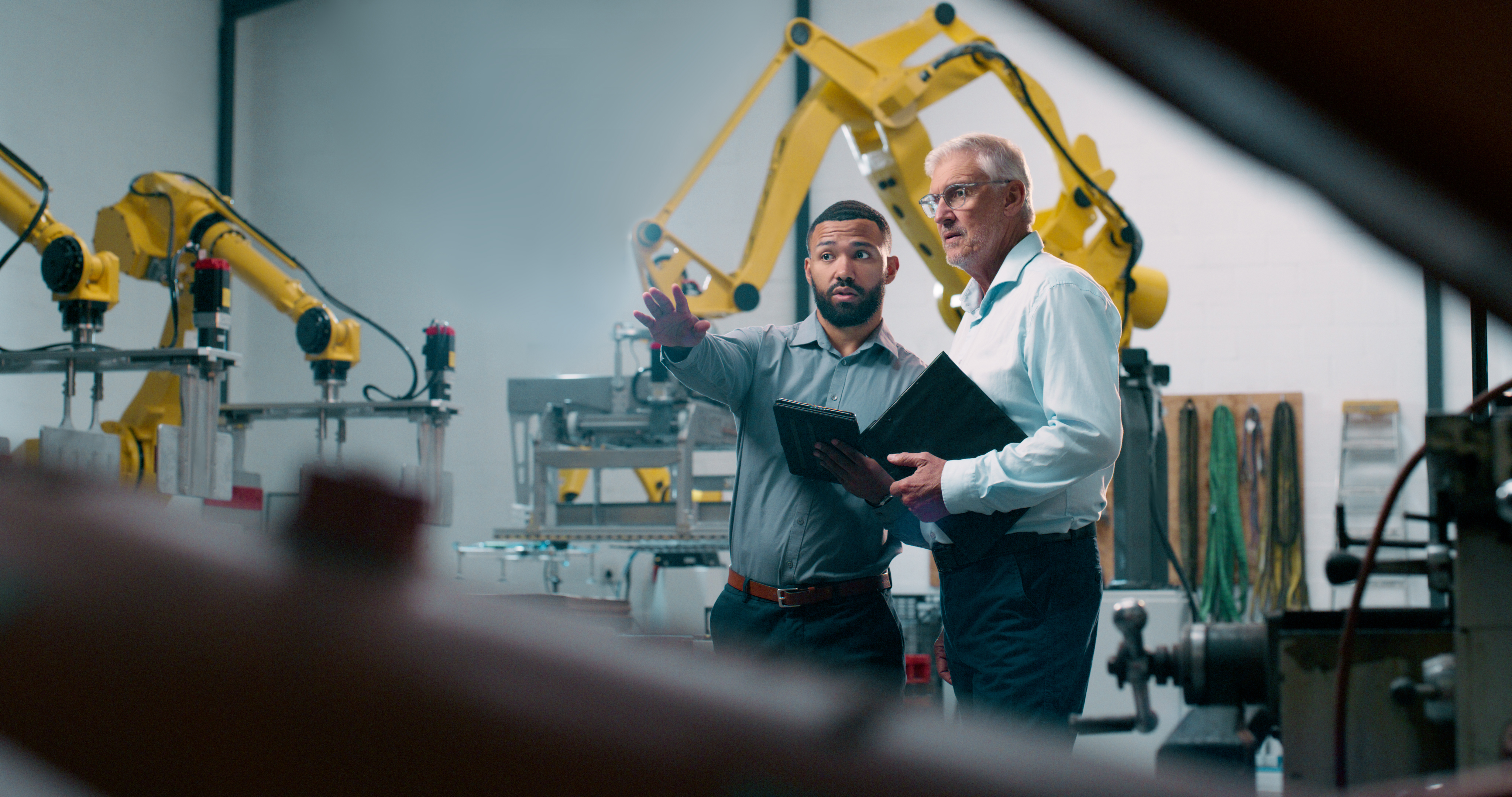 Two professionals discussing automated production equipment in an industrial setting